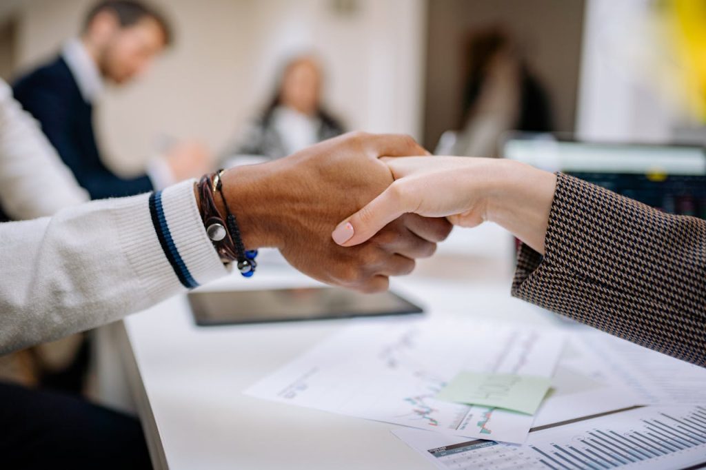 close-up-of-a-handshake-7693153 Diverse business professionals exchanging handshake in an office environment, symbolizing agreement.